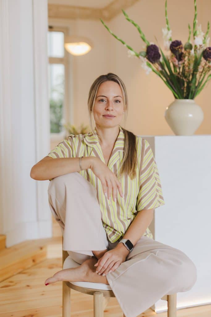 Psychotherapeutin Anne-Marie Trenschel sitzt auf Stuhl modern entspannt professionell